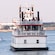 A double deck boat, identified by a sign as the Samuel Clemens, carries passengers in Boston Harbor